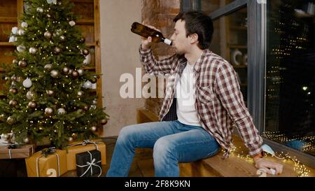 Problems of alcoholism in loneliness, sadness and melancholy during pandemic covid 19. Male removes mask from coronavirus, drinking wine from bottle Stock Photo