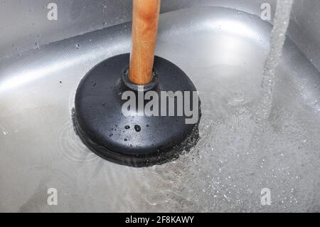 Plunger and clogged kitchen sink. Pipe cleaning concept. Sanitary engineering work. Stock Photo