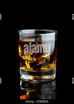 Whiskey in the glass with ice on black background with reflection. Close up view. Stock Photo