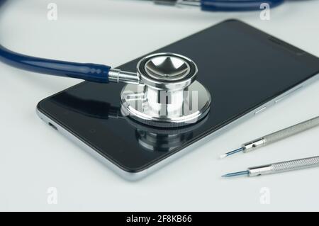 Stethoscope on the smartphone on a grey background. Phone repair and service concept. Concept a health of device. Stock Photo