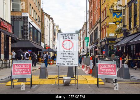 London, United Kingdom. 14th April 2021. Pedestrian Zone and Covid-19 Temporary Restrictions signs in Frith Street. Restaurants, pubs and bars in Soho have reopened after almost four months.