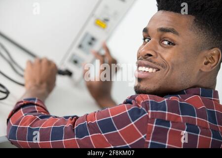 portrait of man plugging power cable into electrical device Stock Photo