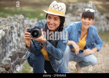 two female photographer crouching near a wall Stock Photo