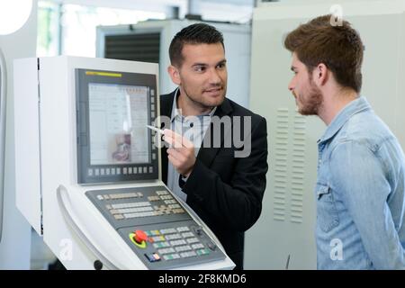 engineer showing apprentice how to measure cad drawings Stock Photo