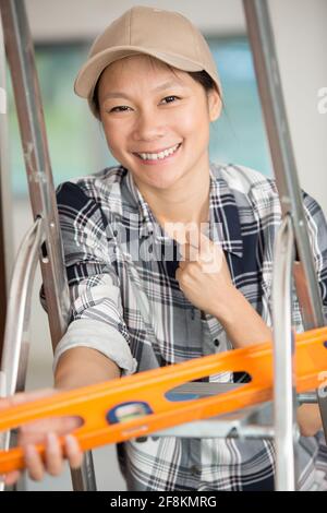 smiling female worker using a spirit level Stock Photo