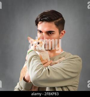 Man hugs and kissing cute Devon rex cat Stock Photo