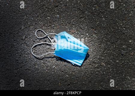 Horizontal shot of a blue paper mask discarded on road Stock Photo