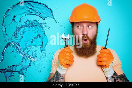 Incompetent worker plumber is unsure about his work. cyan background Stock Photo