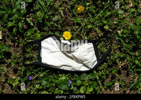 Horizontal shot of a cloth mask from pandemic tossed in grass Stock Photo