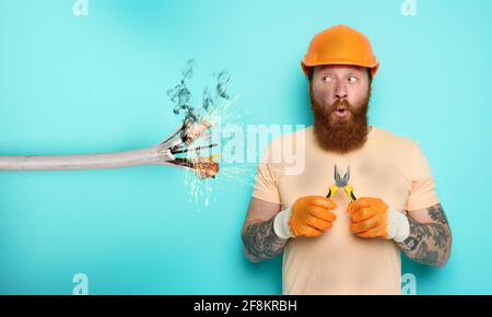 Incompetent worker electrician is unsure about his work. cyan background Stock Photo