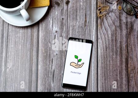 A Mobile phone or cell phone laid on a wooden table showing the Pocket sign language app on screen Stock Photo