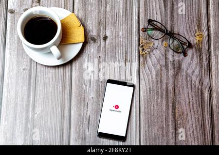 A Mobile phone or cell phone laid on a wooden table showing the Open Table app on screen Stock Photo