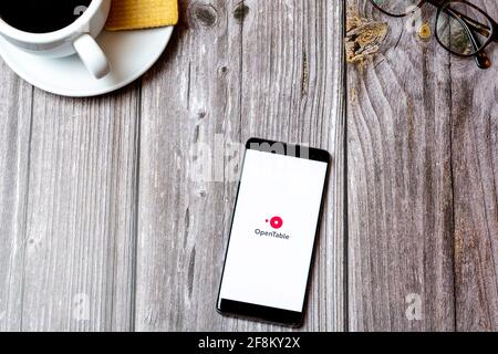 A Mobile phone or cell phone laid on a wooden table showing the Open Table app on screen Stock Photo