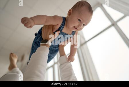 Home portrait of a baby boy with mother on the bed. Mom holding and kissing her child. Mother's day concept Stock Photo