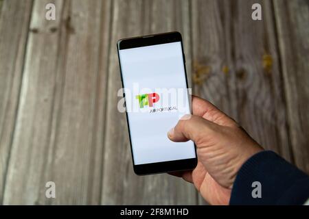 A Mobile phone or Cell phone being held in a hand showing the Tap Air Portugal app on screen Stock Photo