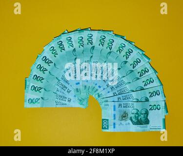 Top view of numerous Mexican two hundred peso banknotes isolated on yellow background Stock Photo