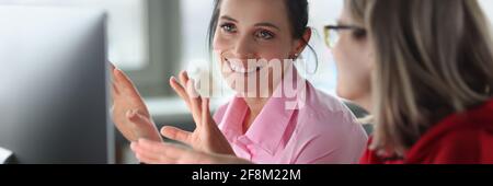Two smiling women are sitting at computer. Stock Photo
