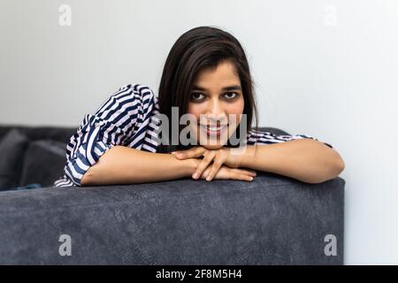 Happy young indian woman lying on couch and relaxing at home Stock Photo