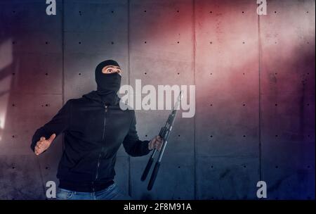 Thief with balaclava and wire cutter was spotted trying to steal in a apartment from the security alarm system. Scared expression Stock Photo