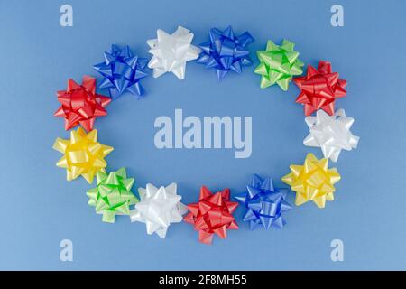 Circle Frame of colorful artificial Rose Flowers from Plastic Ribbon for Decorating Gift in Flat lay. Festive Background . Stock Photo