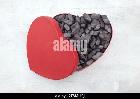 Cardbox in form of heart with black  Packing peanuts protective granules Styrofoam chips Background. love or valentine day concept Stock Photo