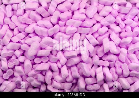 Packing peanuts purple  bubbly plastic protective granules Styrofoam chips Background Safe packing concept, Foam popcorn cushioning material in shippi Stock Photo