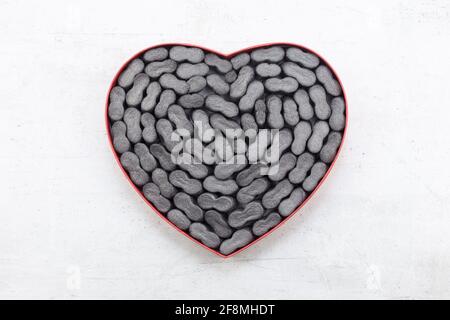 Cardbox in form of heart with black  Packing peanuts  bubbly plastic protective granules Styrofoam chips Background. love or valentine day concept Stock Photo