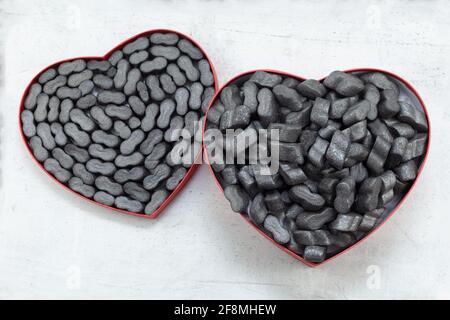 Cardbox in form of heart with black  Packing peanuts  bubbly plastic protective granules Styrofoam chips Background. love or valentine day concept Stock Photo