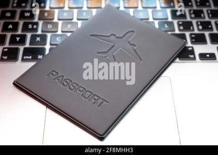 a passport over a laptop On Computer Keyboard . Planning a trip, buying tickets online. Blurred background Stock Photo