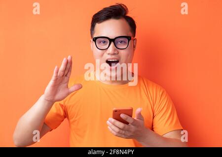 Young Asian man holding the phone with a surprised expression Stock Photo