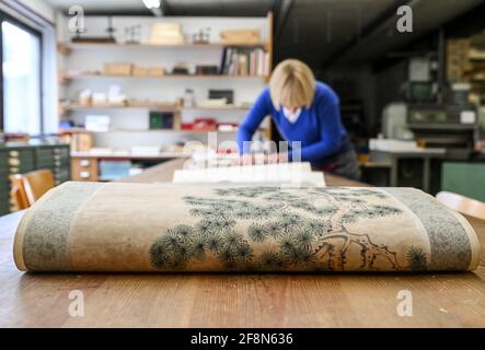Berlin, Germany. 13th Apr, 2021. Bookbinder Julia Flögel works on the restoration of a Chinese scroll painting in the paper workshop in Friedrichshagen. In the joint business of her and Frauke Grenz, all damage to books, letters, documents, maps, travel cases, boxes as well as pictures are repaired here. They also produce books as one-offs or in smaller editions and offer numerous courses. The shop is located in an old print shop with old drawers full of metal type, as well as machines for embossing, cutting and binding. Credit: Jens Kalaene/dpa-Zentralbild/ZB/dpa/Alamy Live News Stock Photo