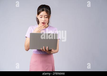 Young Asian woman using laptop on grey background Stock Photo