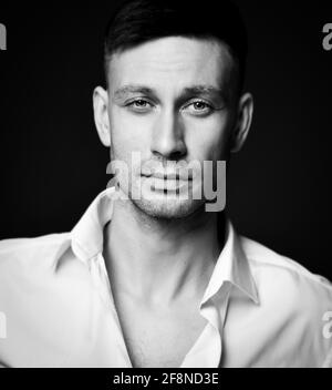 Black and white portrait of calm friendly brunette man in unbuttoned formal shirt office worker Stock Photo