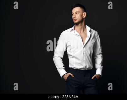 Portrait of young self-confident businessman in official suit trousers and shirt stands looking aside at copy space Stock Photo