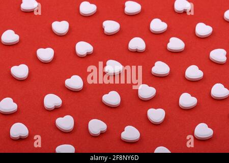 Heart shaped pills on a red background Medicines that help people Stock Photo