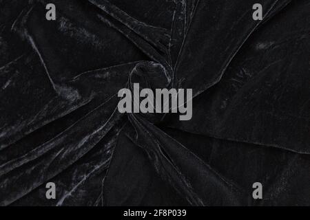 Colored black textile satin fabric folded in folds and waves with highlights and texture shimmers in the light Stock Photo