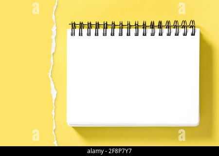 Spiral notepad book mockup and torn paper border for presentation of your design. Yellow background Stock Photo