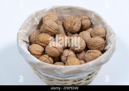 Walnuts in a wicker basket on a white background. Stock Photo