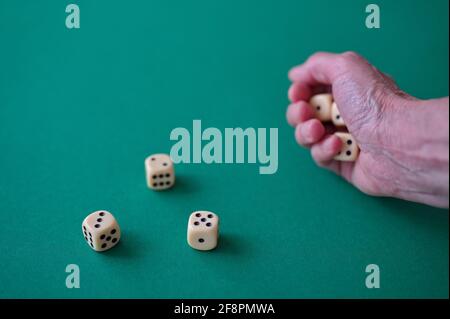 Cropped photo of hand throwing dices on the green table Stock Photo