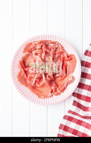 Sliced carpaccio. Raw beef meat on plate. Top view. Stock Photo