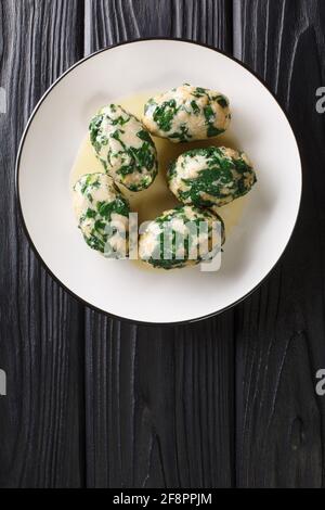 Spinach and Cheese Breadcrumb Dumplings Strangolapreti close-up in a plate on the table. Vertical top view from above Stock Photo