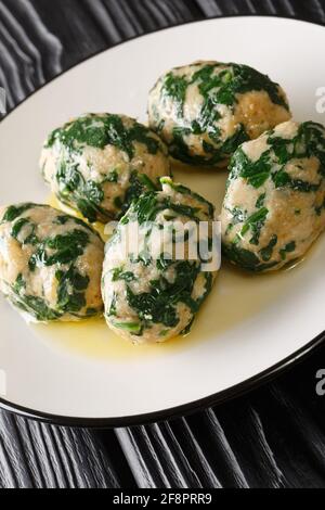 Strangolapreti in Trentino Italian bread and spinach dumplings close-up in a plate on the table. Vertical Stock Photo