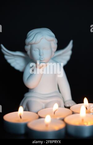 Angel with candles in front of it, black background, mourning card, card, postcard Stock Photo