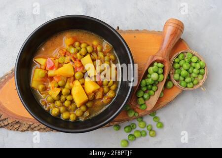 Indian popular homemade Aloo Matar. Potatoes and peas curry. Vatana batata bhaji or sabzi. with cooking ingredients along with copy space. Stock Photo