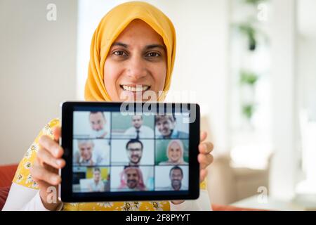Muslim womah holding tablet with zoom conference screen Stock Photo