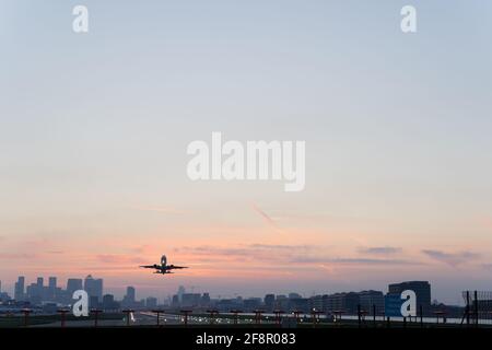 airplane take off from London city airport into warm and clear sky at sunset, UK Stock Photo