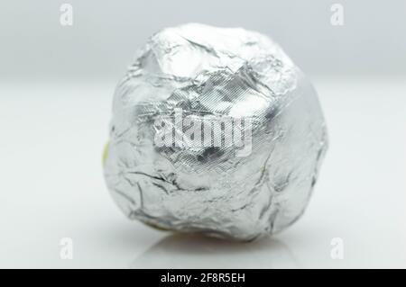 round chocolate candy in a white shiny package on a gray background . isolated, close-up Stock Photo