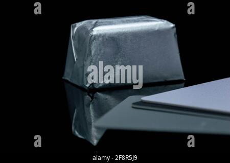 Abstract, creative photo of rectangular shaped candy in shiny packaging on a black background . close-up Stock Photo