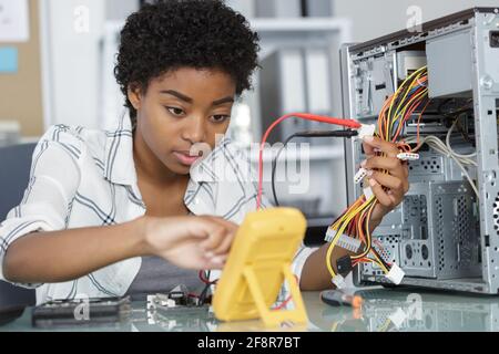 young female computer repairer using multimeter Stock Photo