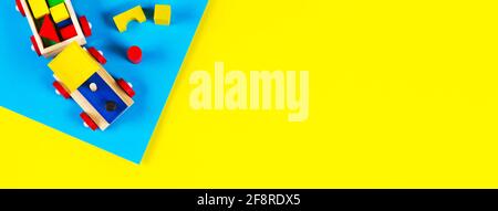 Baby kid toys banner background. Wooden toy train with colorful blocks on light blue and yellow background. Top view Stock Photo